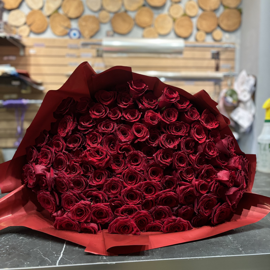 A luxurious bouquet of 101 deep red roses, elegantly arranged with rich petals and a bold, romantic color that exudes love and passion.