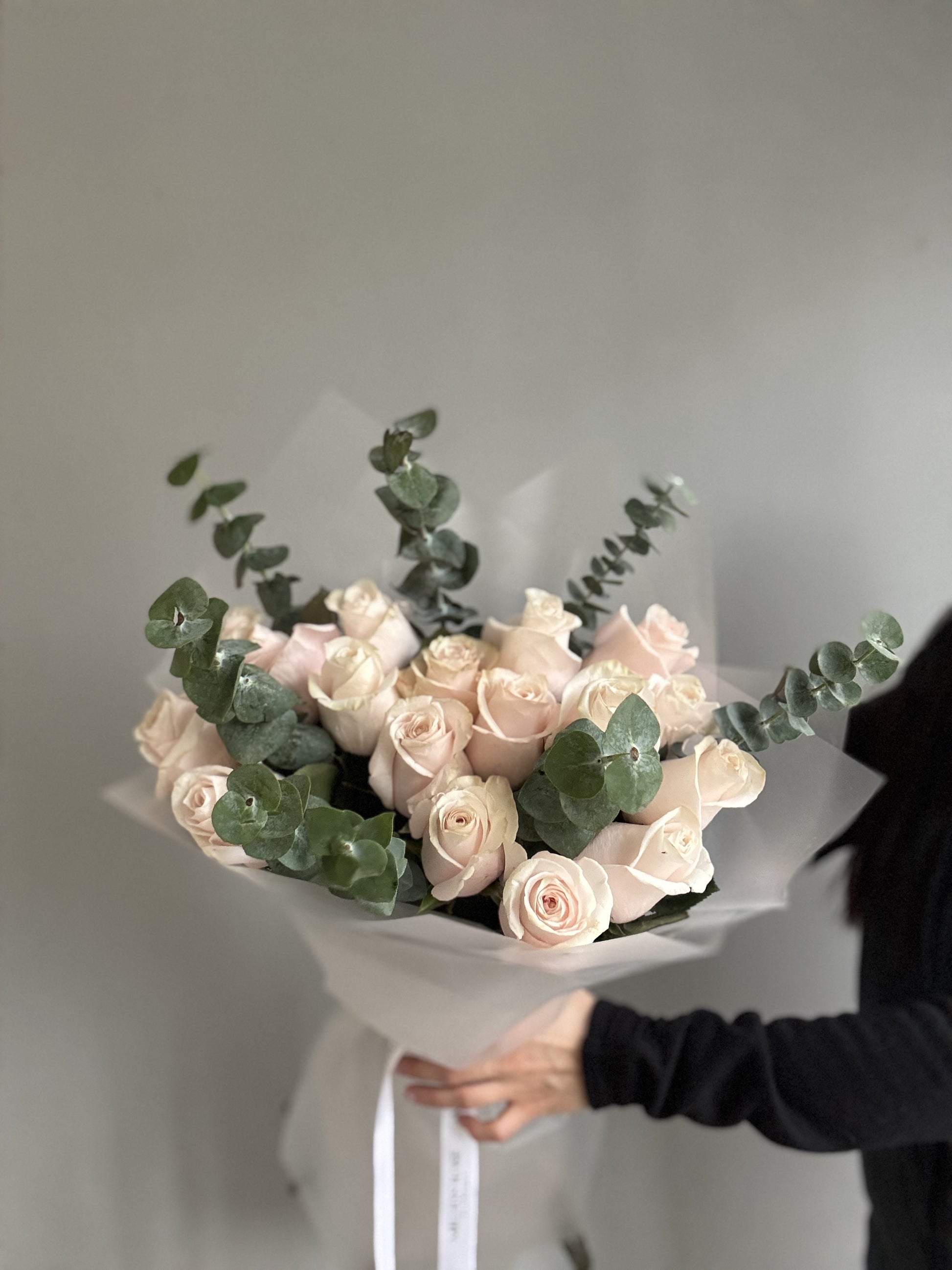 A Pink Blush Bouquet featuring soft pink and blush-colored roses, peonies, and baby’s breath, arranged delicately to create a romantic and elegant floral display. 